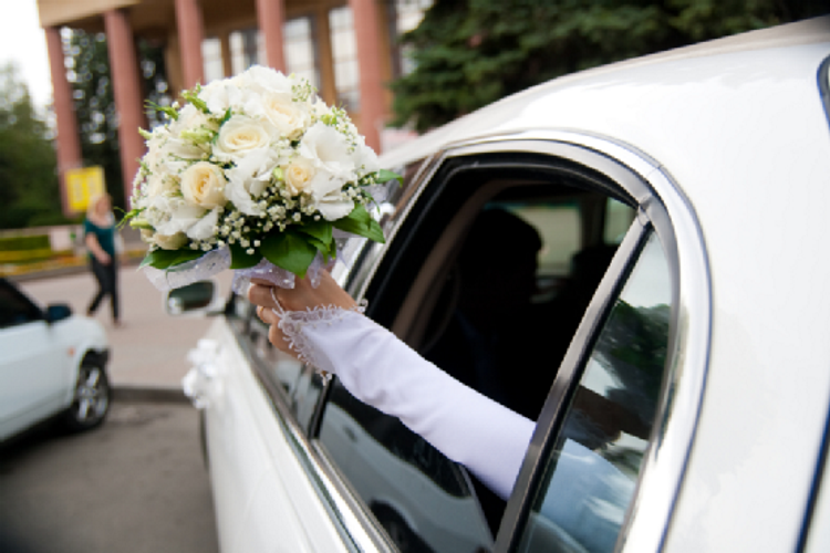 bride holding a bouquet in a white limo